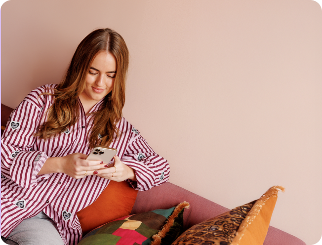 Een vrouw die op de bank zit met haar telefoon in haar hand