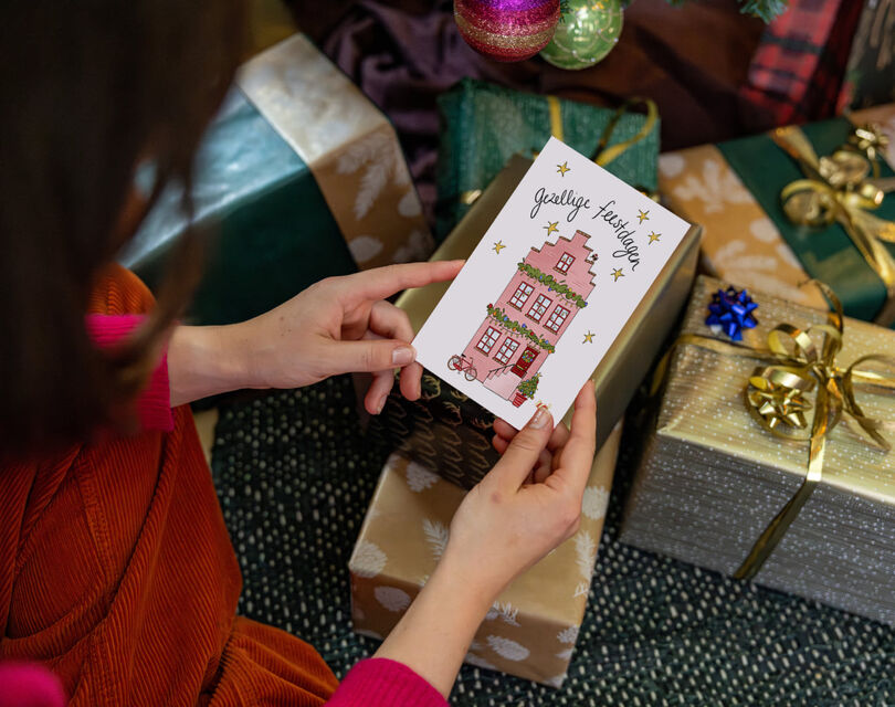 Vrouw die kerstkaart vasthoudt met de tekst 'gezellige feestdagen!'