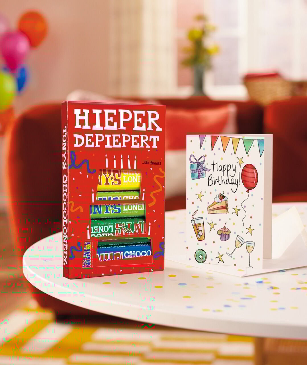 Een doosje met verschillende Tony Chocolonely repen en een veraardagskaart op een tafel