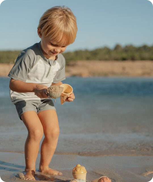 Een jongetje op het strand die aan het spelen is 