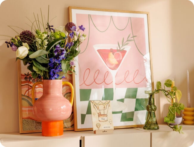 Een kast met daarop een vaas met bloemen en een schilderij