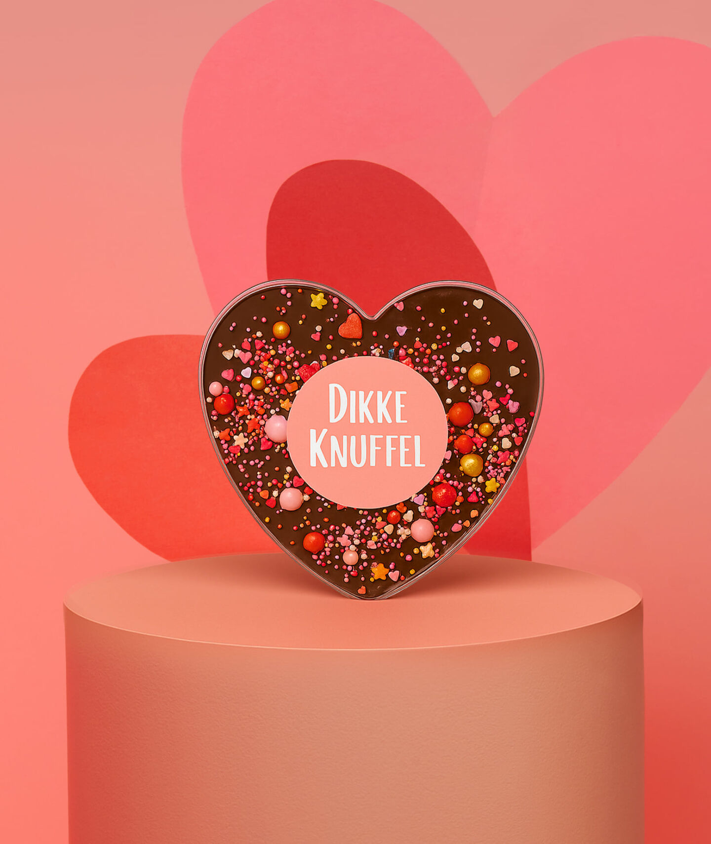 Een chocoladehart met de tekst 'dikke knuffel' tegen een rode hartjesachtergrond